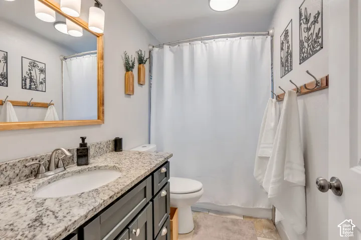 Vanity with a granite-style countertop, undermount sink, and dark cabinetry