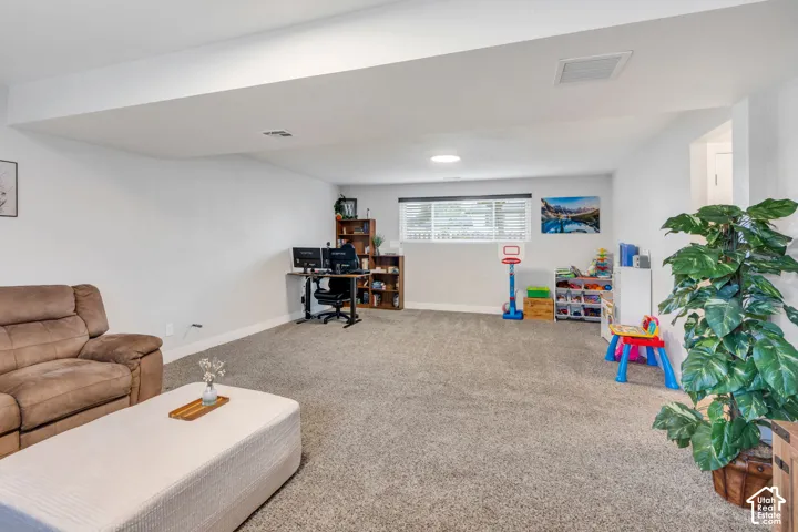 Carpeted room featuring a window with horizontal blinds, overhead lighting, and white walls