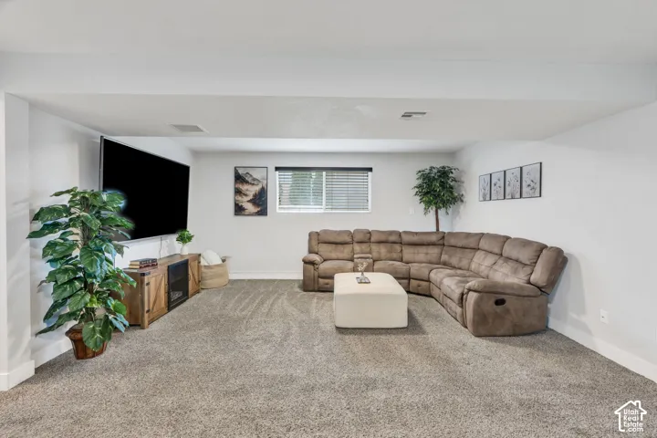 Carpeted floor with neutral tones, white walls, and a window with horizontal blinds