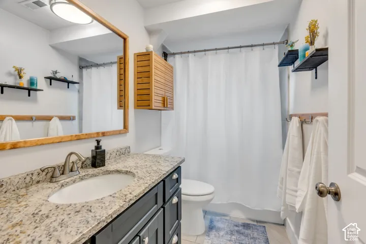 Vanity with a granite-style countertop, undermount sink, and dark wood-finish cabinetry