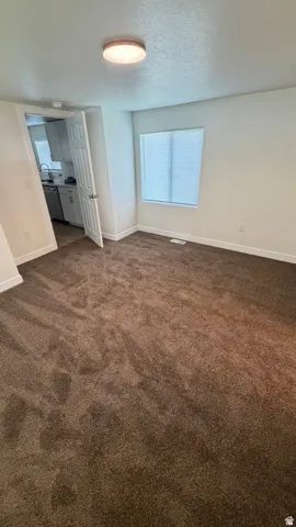Brown carpet flooring, white walls, and a window with horizontal blinds