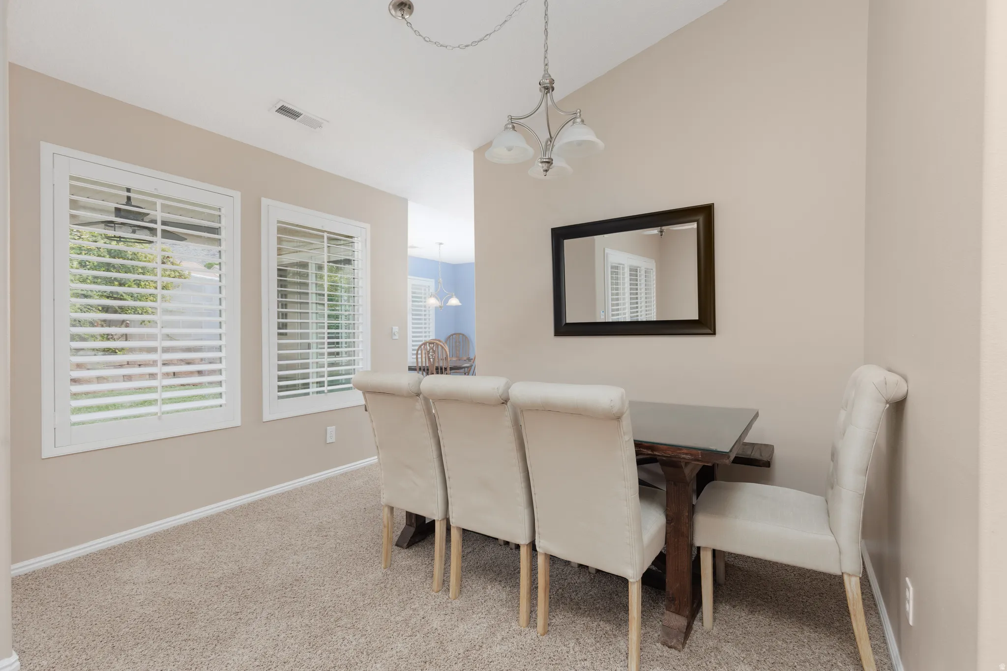 Vaulted ceiling, recessed lighting, dual windows with plantation shutters, carpeted flooring, and a chandelier lighting fixture