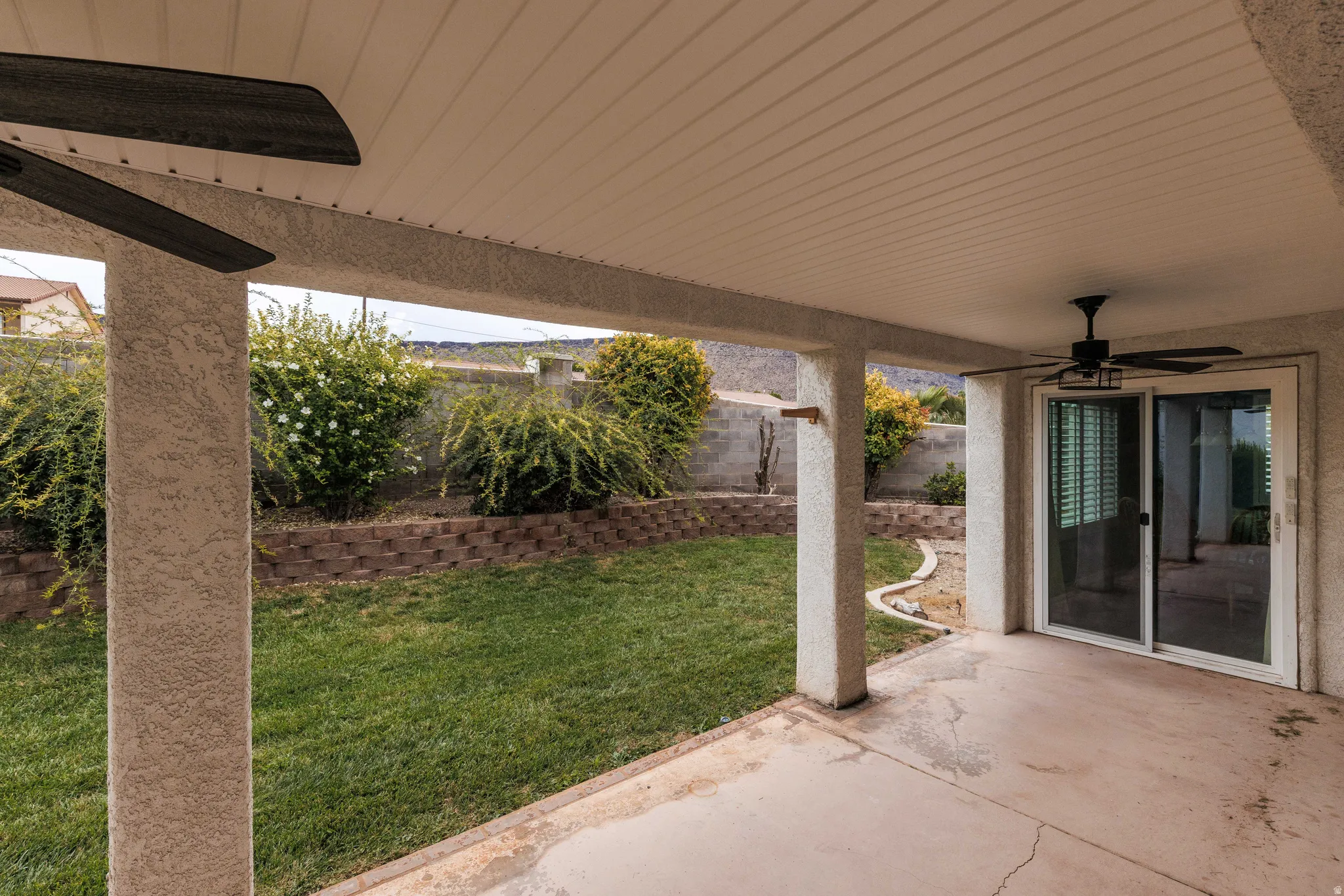 Covered patio featuring a ceiling fan, concrete flooring, and sliding glass doors