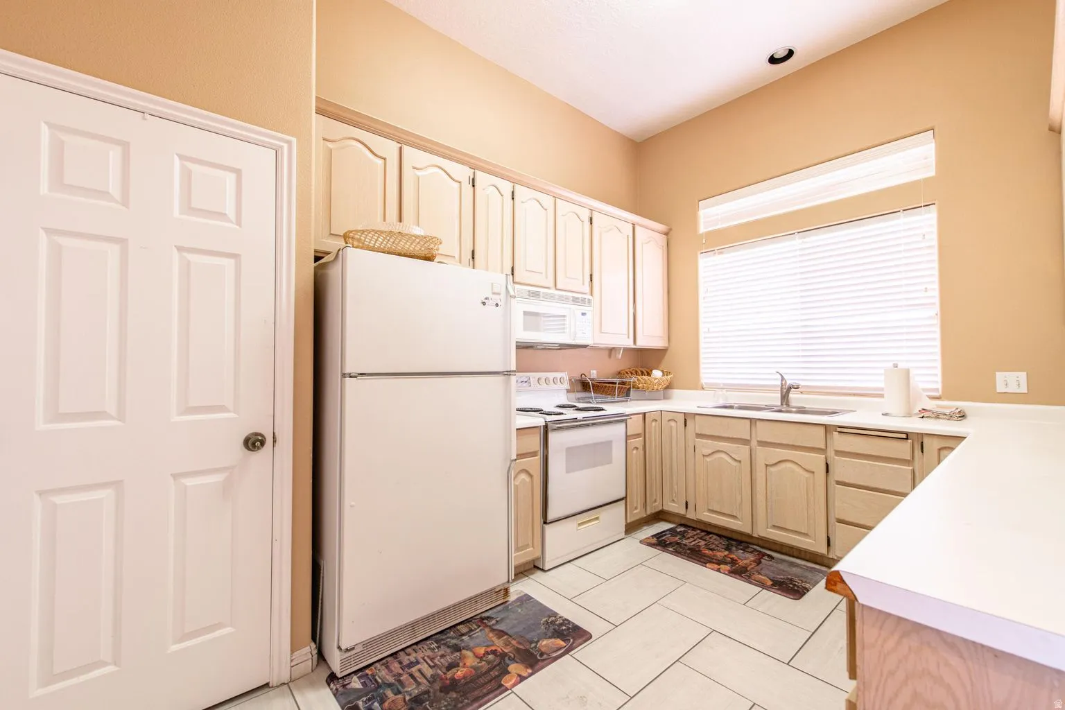 Kitchen featuring white tile flooring, white appliances, and light-toned cabinetry