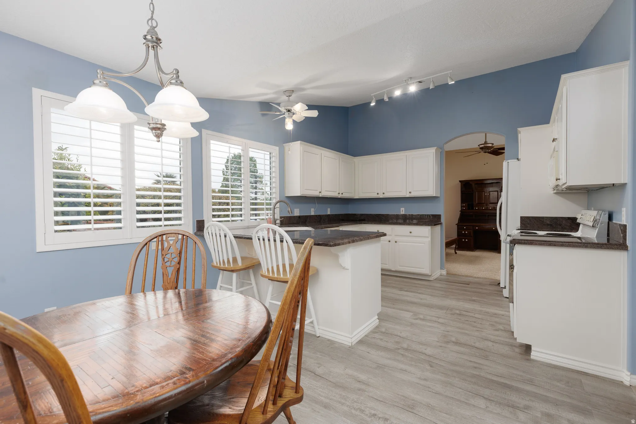 Kitchen featuring white cabinetry, dark countertops, a central island, and light wood-finish flooring