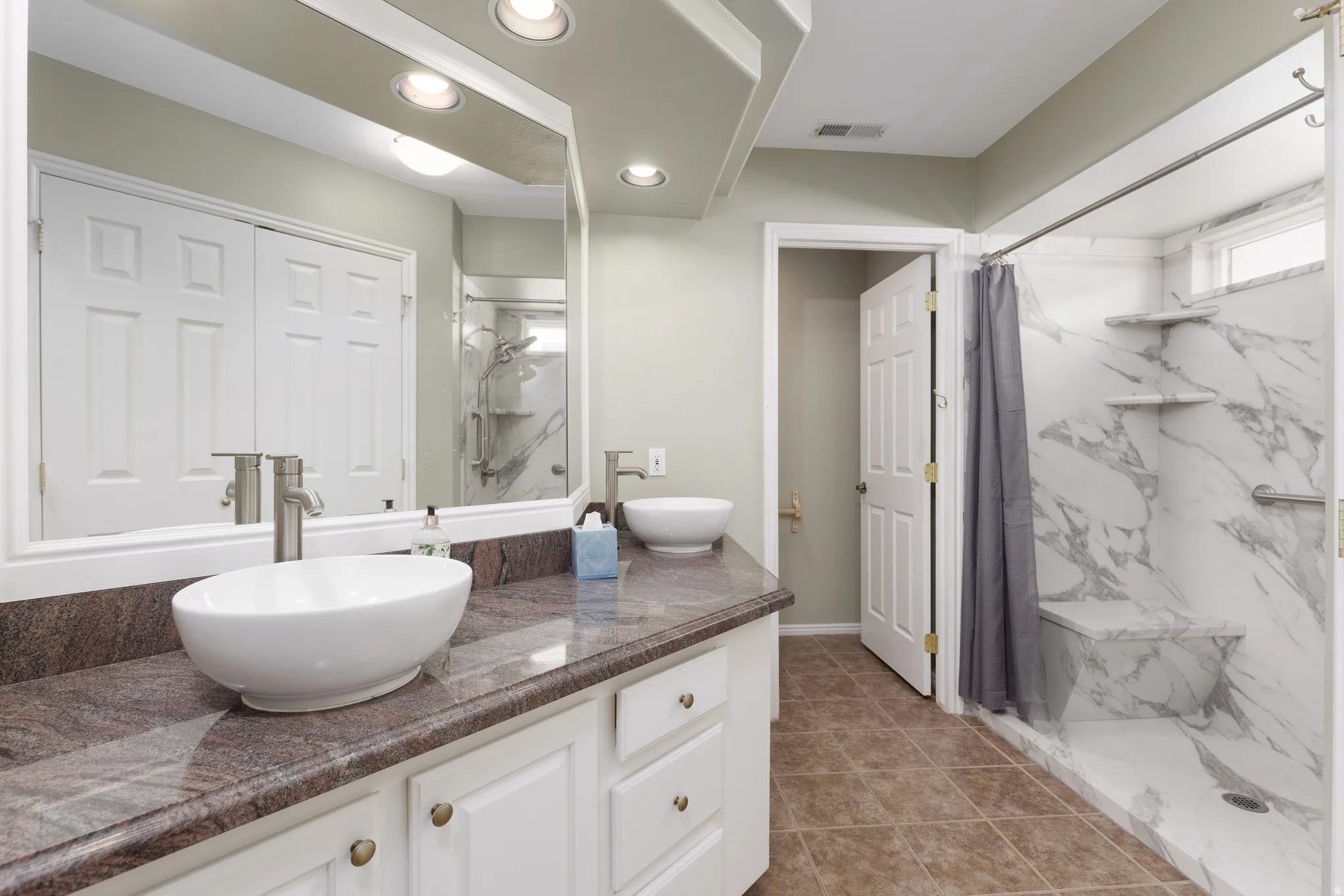 Double vanity with vessel sinks, granite-style countertop, and white cabinetry