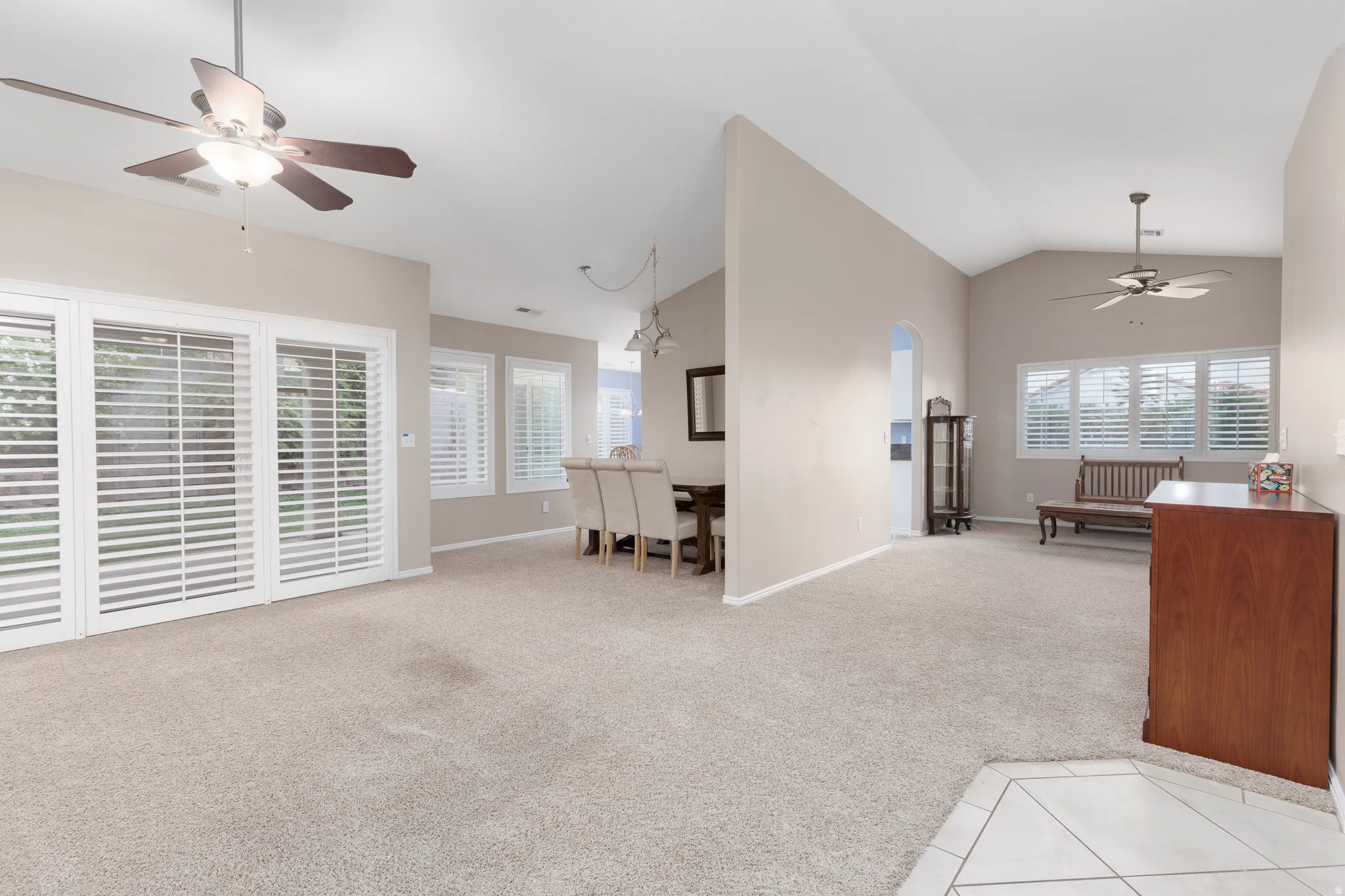Vaulted ceilings, neutral tone carpeting, and ceiling fans