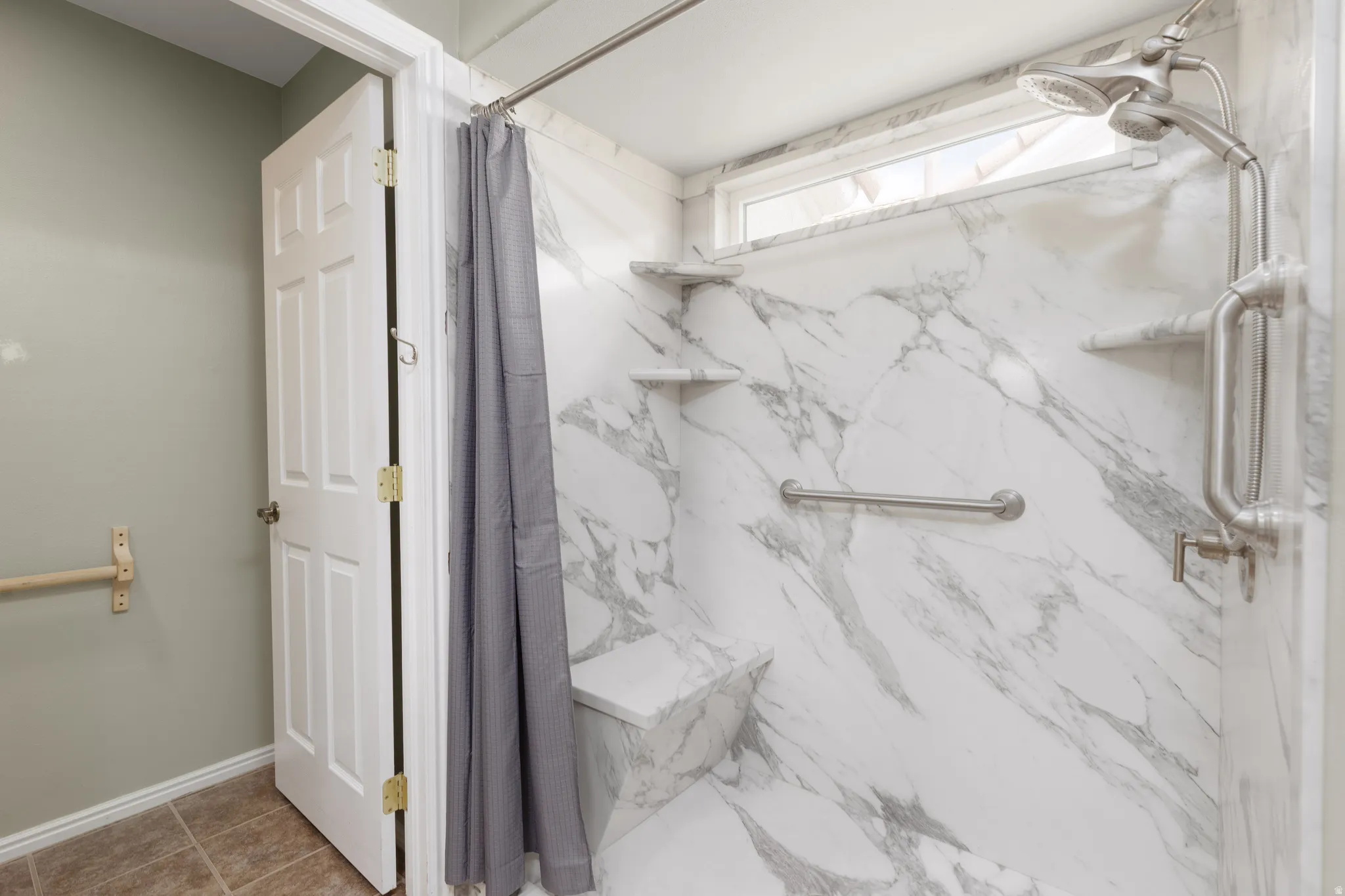 Shower with marble-finish walls, built-in bench, and integrated shelving