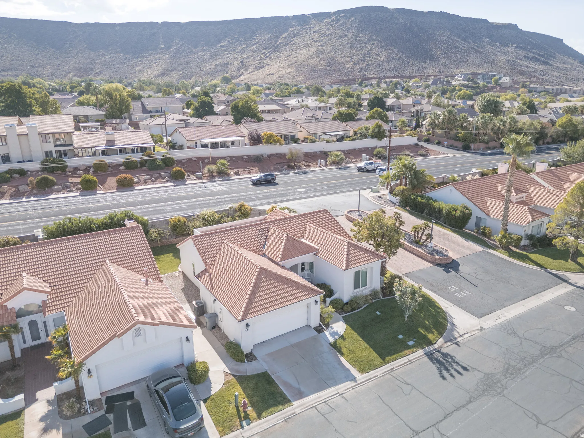 Tile roof residence featuring a front lawn, paved driveway, and mountain backdrop