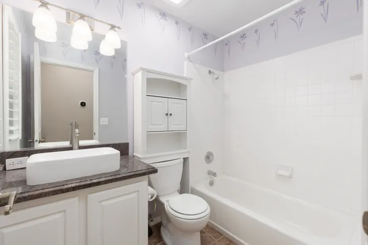 Bathroom featuring a vessel sink, vanity with panel cabinetry, tub/shower combination, and tiled flooring
