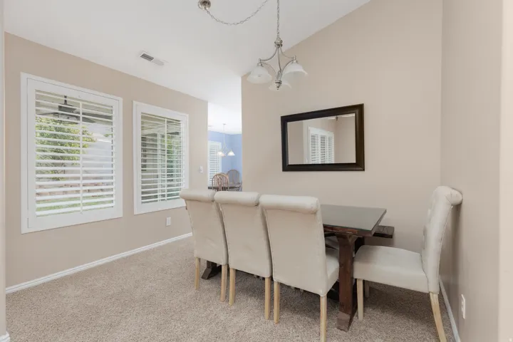 Vaulted ceiling, recessed lighting, dual windows with plantation shutters, carpeted flooring, and a chandelier lighting fixture