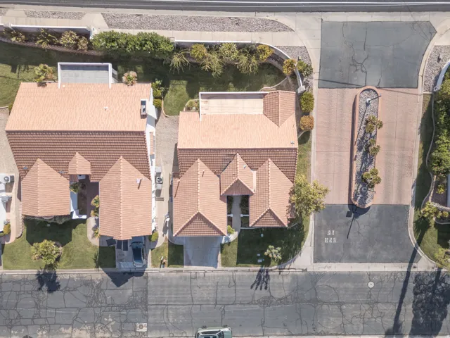 Terracotta tile roofing, manicured landscaping, concrete driveways, and adjacent cul-de-sac