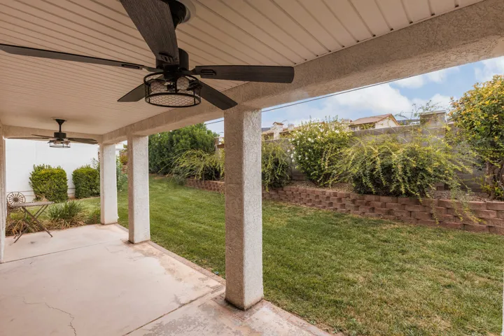 Covered patio with dual ceiling fans, concrete flooring, and support columns