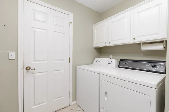 White paneled door, white upper cabinetry with brass hardware, and light-toned wall paint