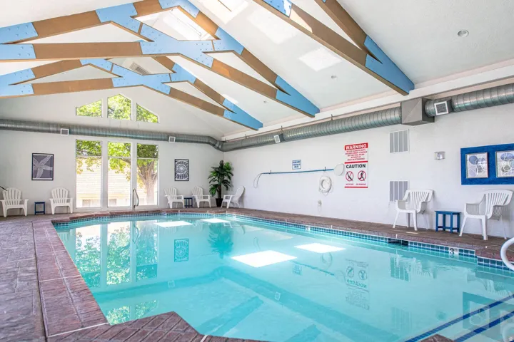 Indoor swimming pool with exposed wood beams, skylights, and large windows