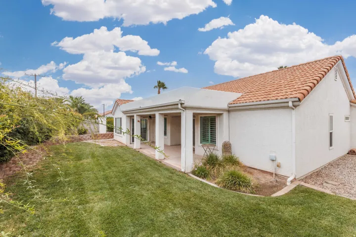 Expansive rear yard featuring a covered patio, terraced landscaping, and a tile roof
