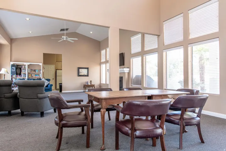Vaulted ceiling with a ceiling fan, a wall of windows with horizontal blinds, and a built-in fireplace