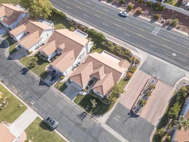 Residential property with terracotta-tiled roofs, a paved driveway, and established landscaping
