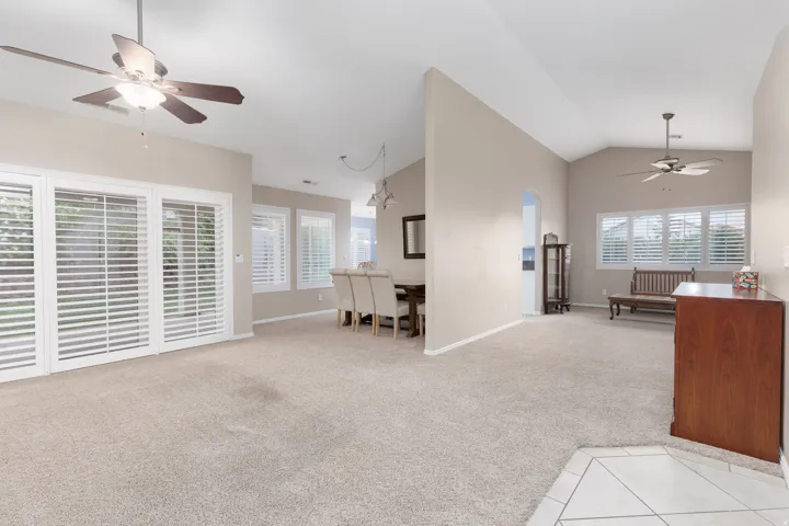 Vaulted ceilings, neutral tone carpeting, and ceiling fans