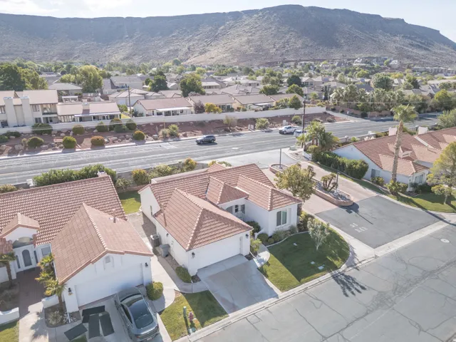 Tile roof residence featuring a front lawn, paved driveway, and mountain backdrop
