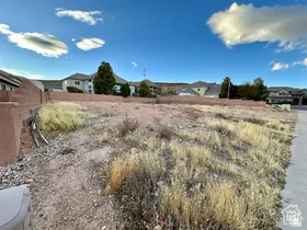 Vacant land parcel with a partial concrete retaining wall and established neighborhood surroundings