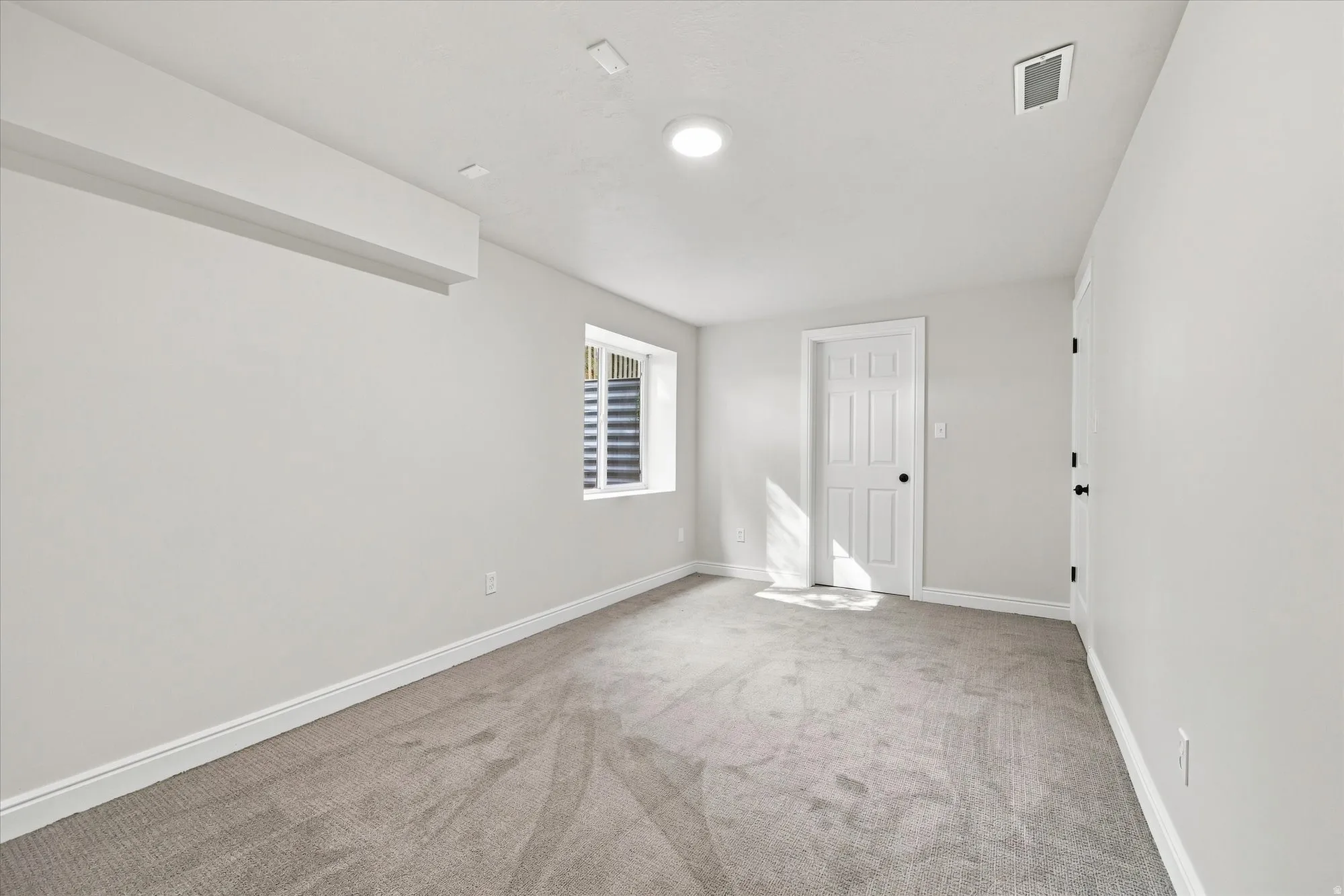 Recessed ceiling lighting, light gray wall paint, gray carpeting, white trim, and a white paneled door