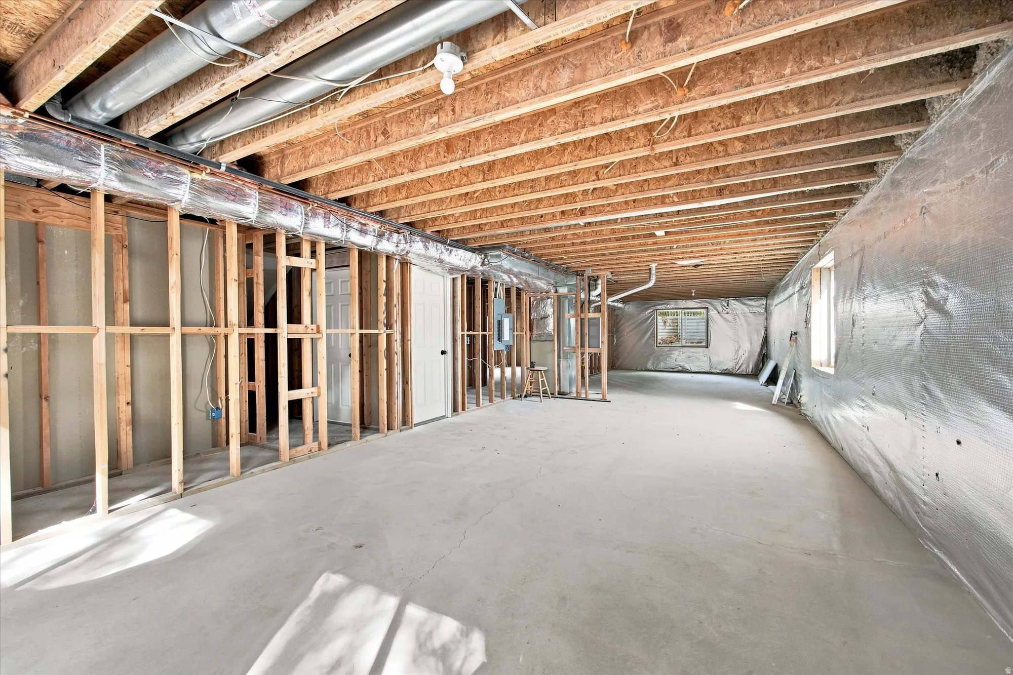 Unfinished basement with concrete flooring, exposed wood ceiling joists, and framed interior walls