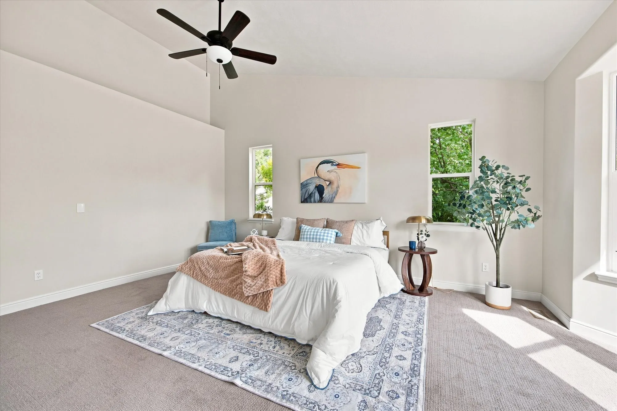 Vaulted ceiling with a ceiling fan, multiple windows, window seating, and neutral wall tones