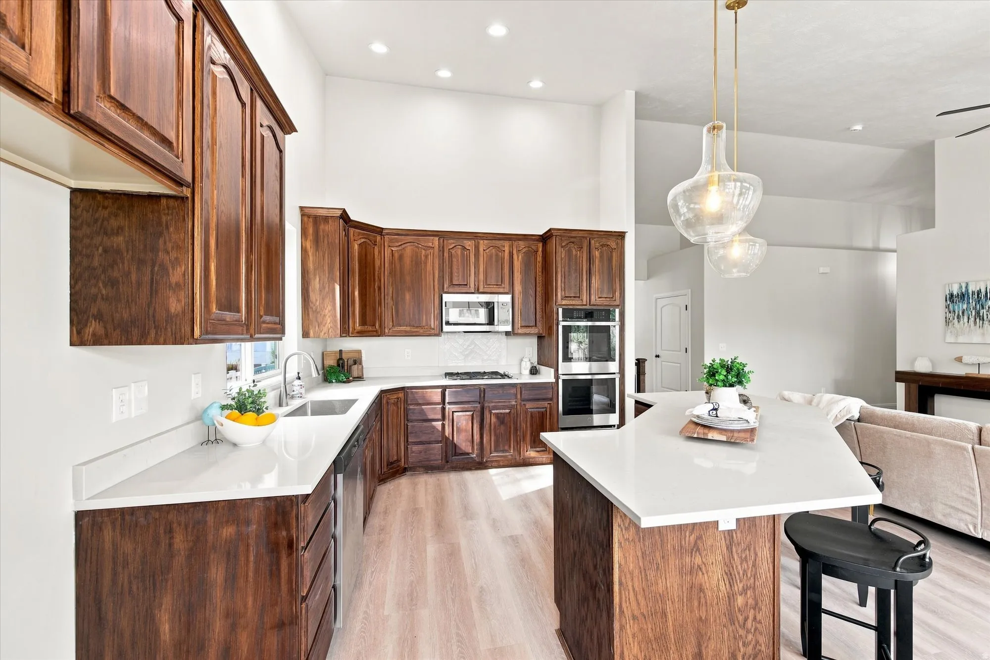Kitchen featuring wood cabinetry, light-toned countertops, integrated stainless steel appliances, and wood-finish flooring