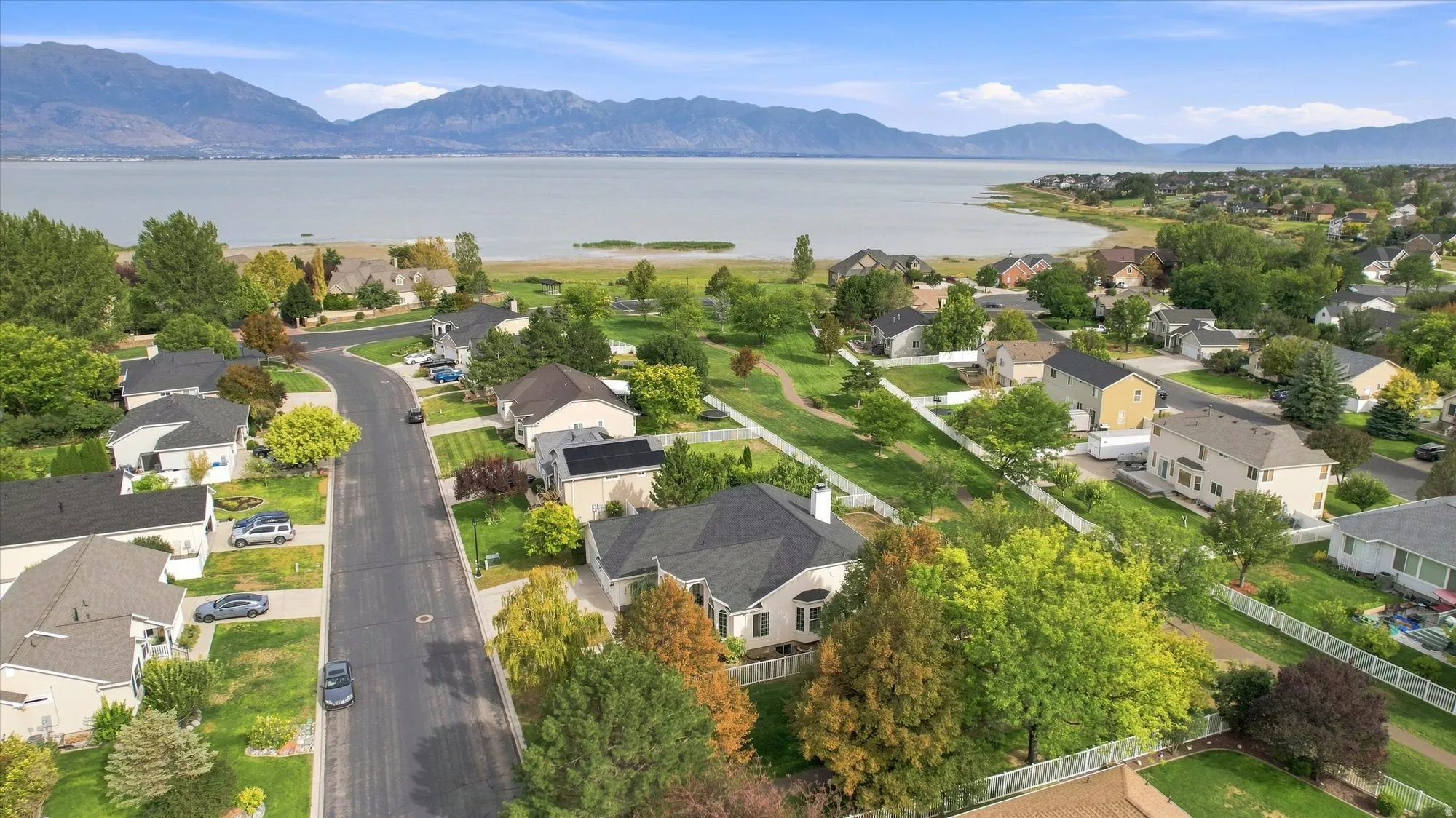 Aerial view of this residential property showcasing manicured landscaping, mature trees throughout the grounds, and a paved driveway