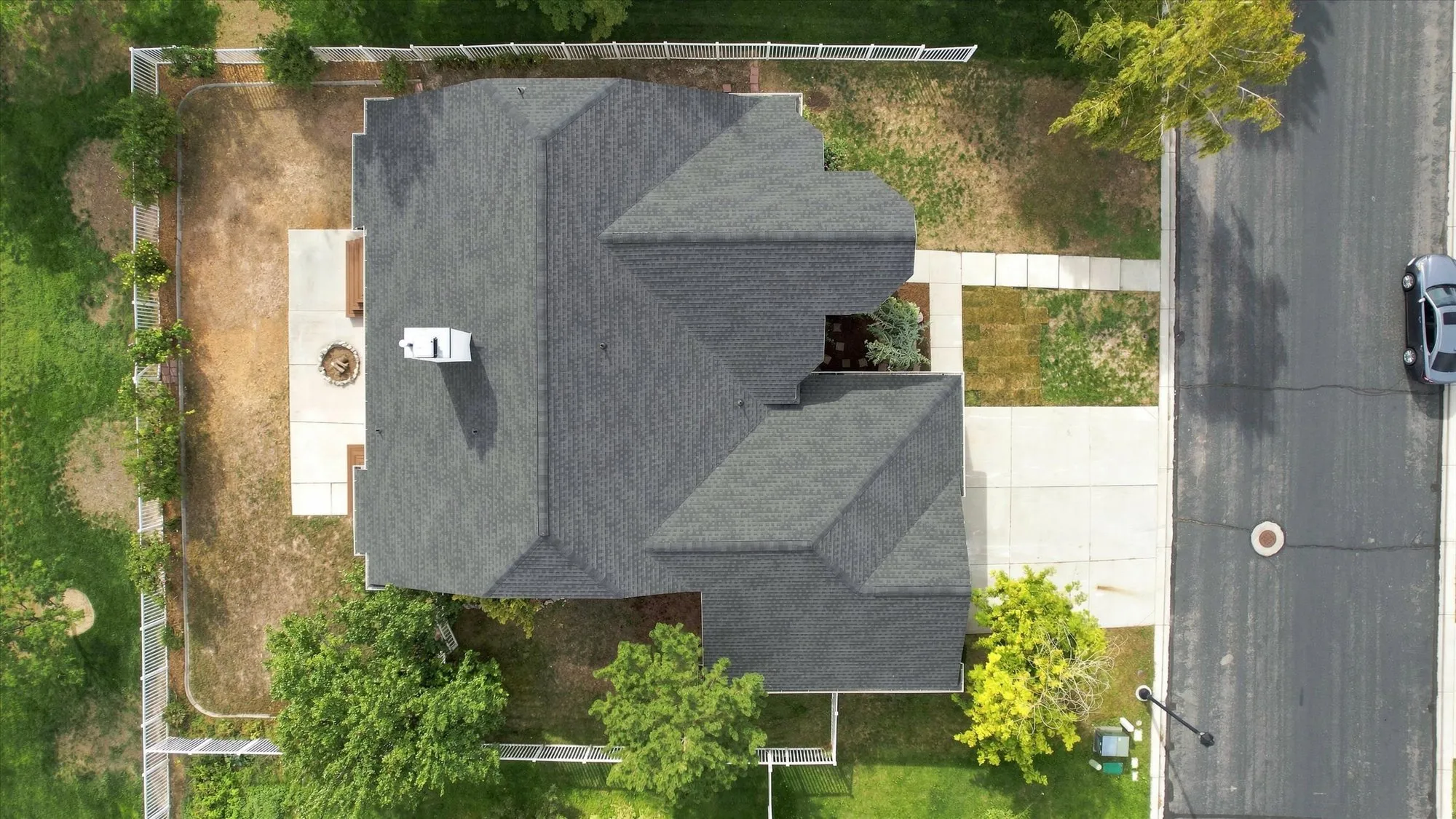Gable roofline, white fence, concrete patio, concrete walkway, and paved street