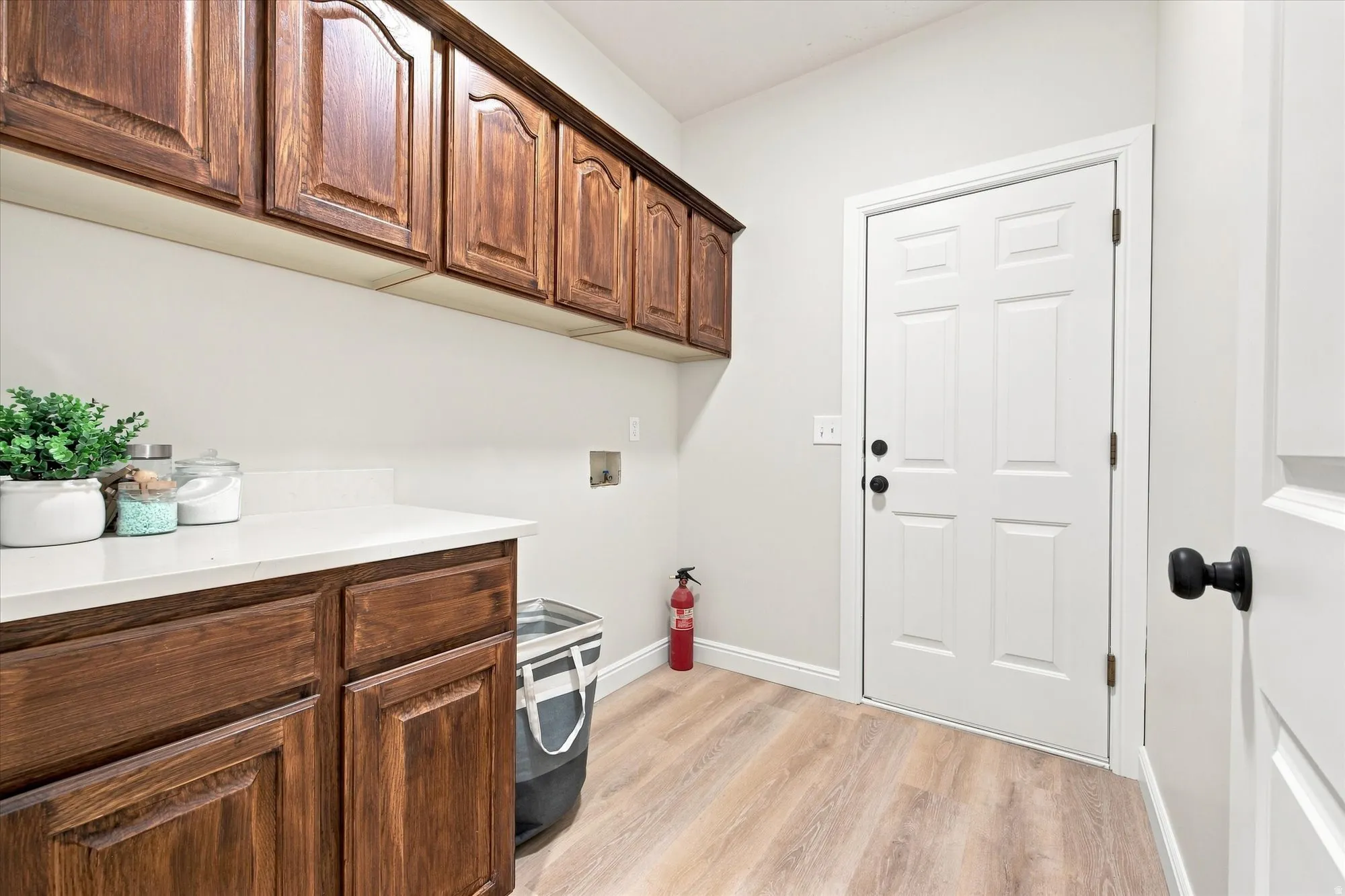 Wood-finish flooring, white walls, and a white door with matte black hardware