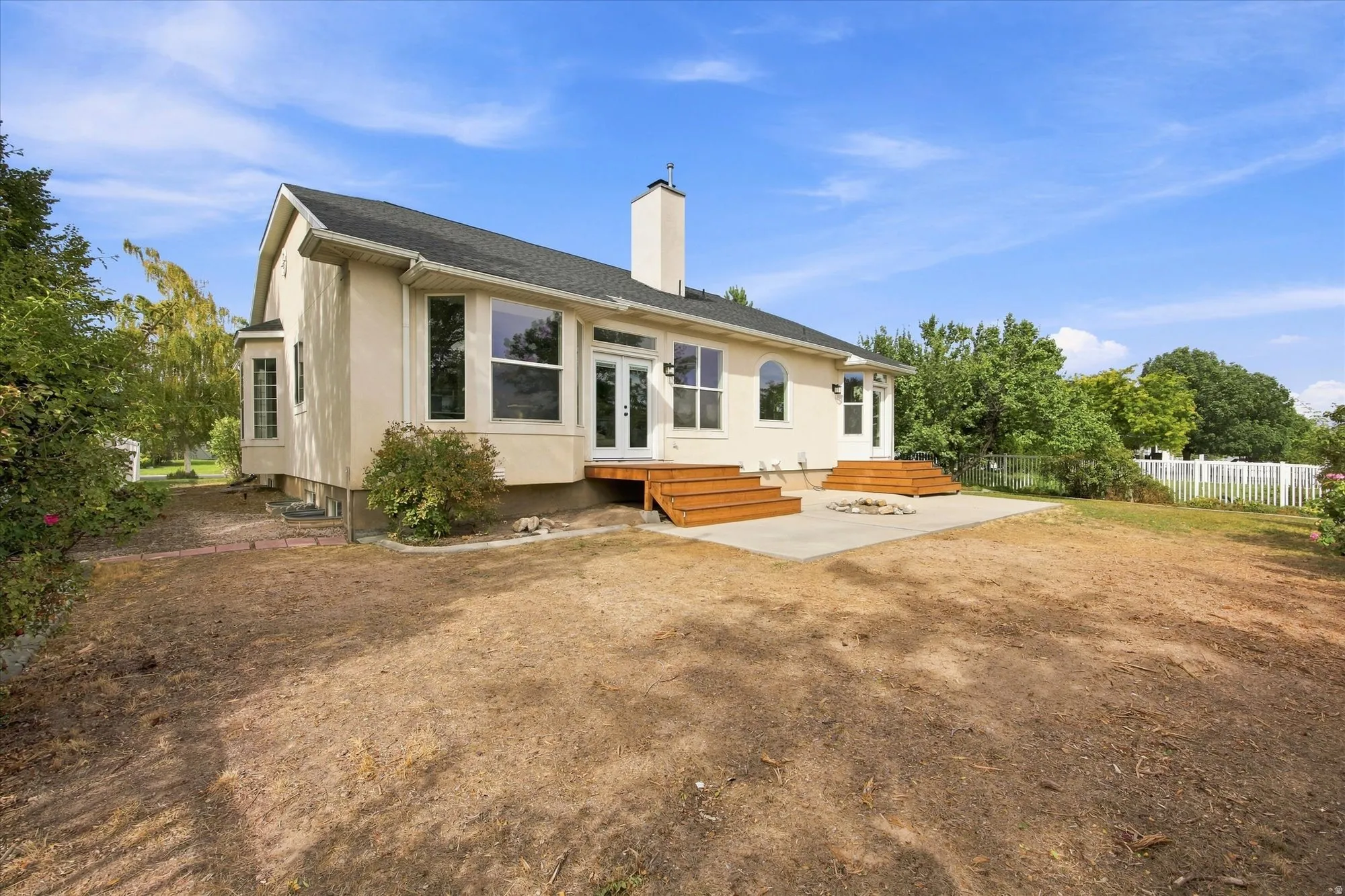 Exterior featuring a stucco finish, multiple windows, and a concrete patio with two sets of wood steps