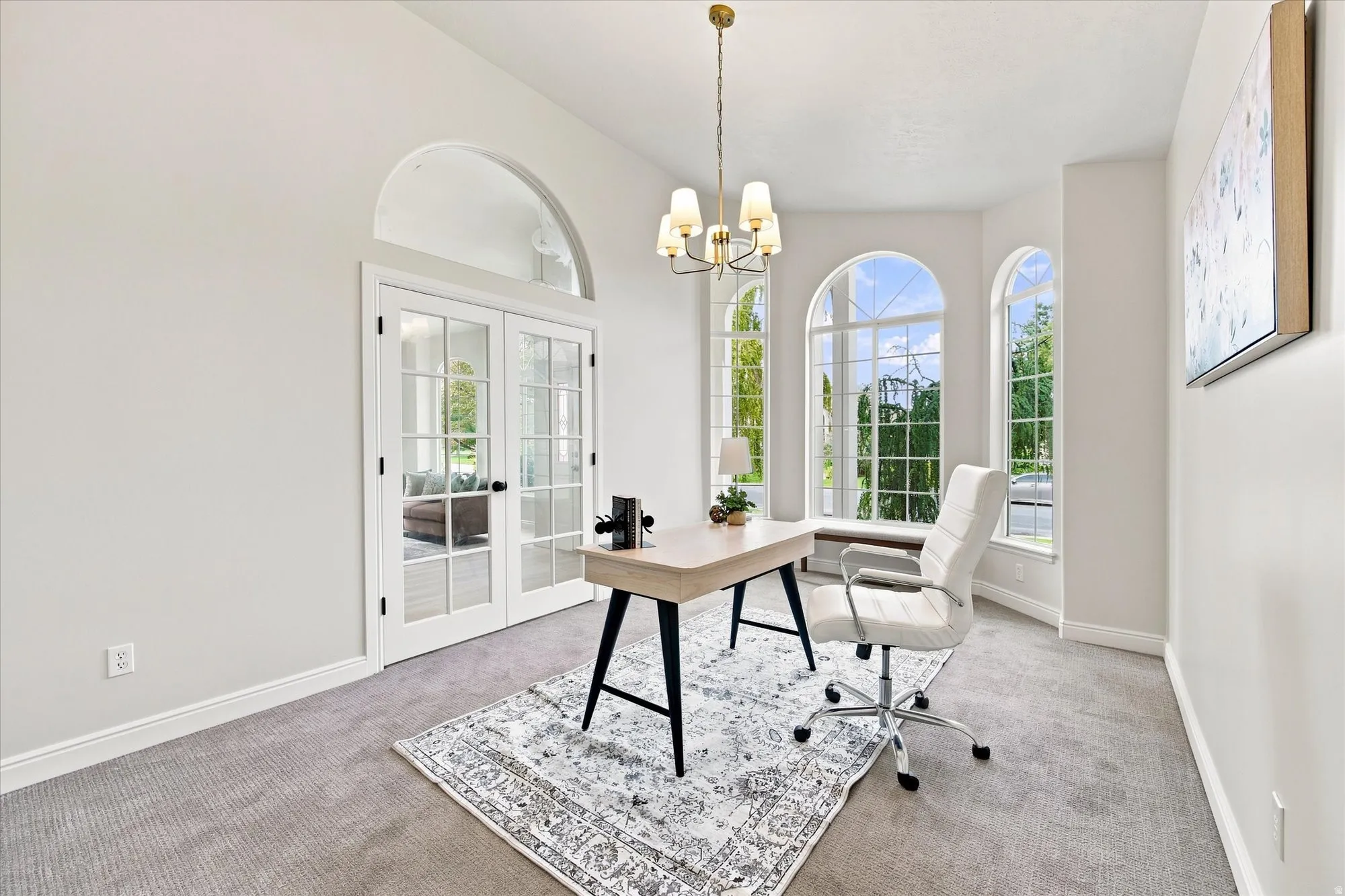 Arched windows with window seating, French doors with transom, and a chandelier lighting fixture