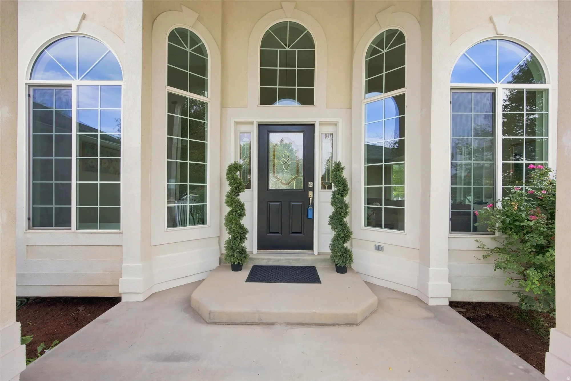Arched transom windows, decorative window grilles, and a recessed panel front door with leaded glass