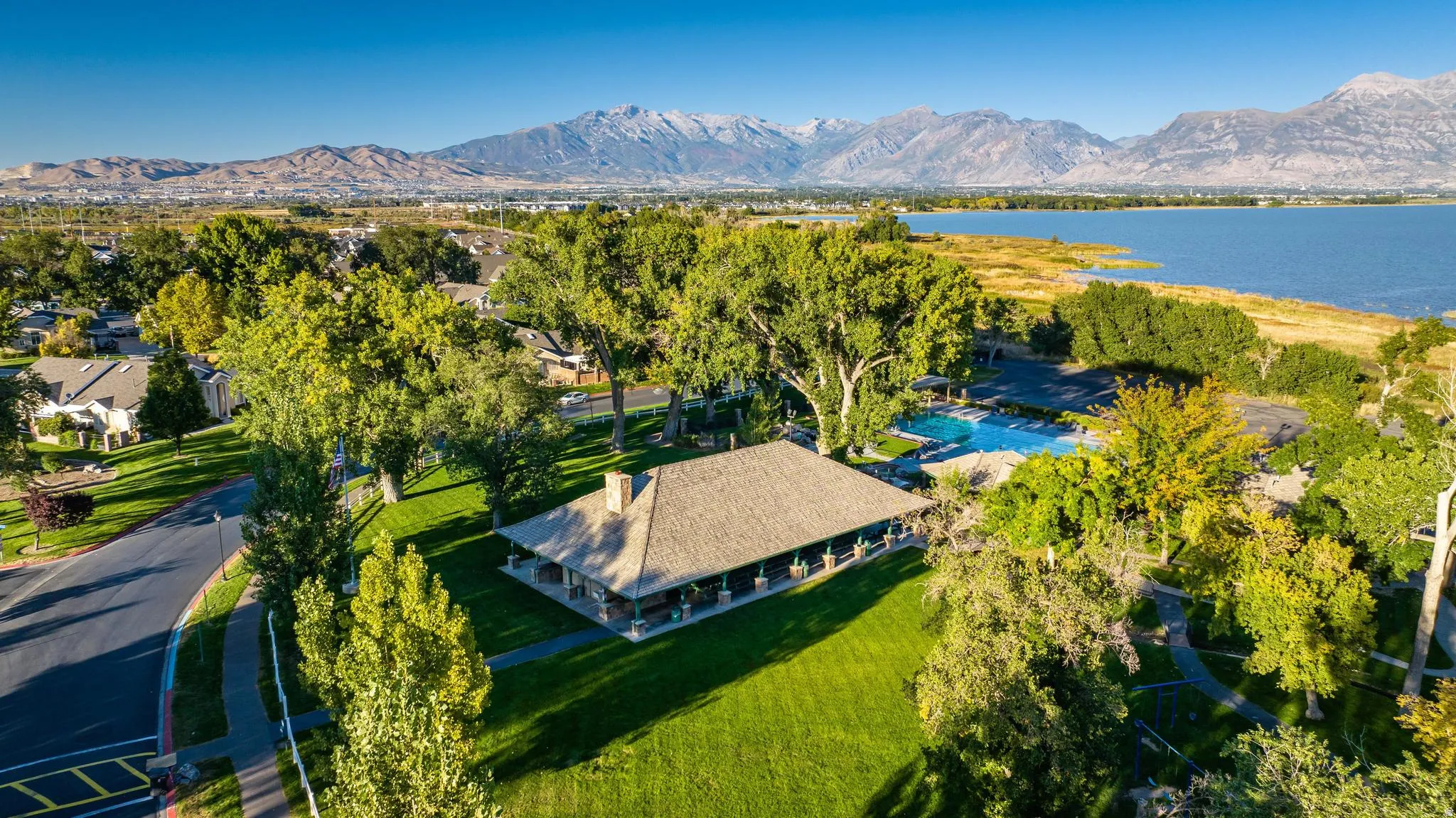 Expansive green spaces and mature trees surrounding  community pavilion with a covered porch