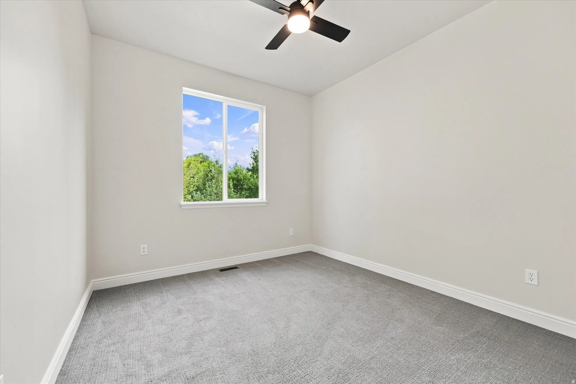 Neutral wall paint, ceiling fan with integrated lighting, carpeted flooring, large window, and white trim