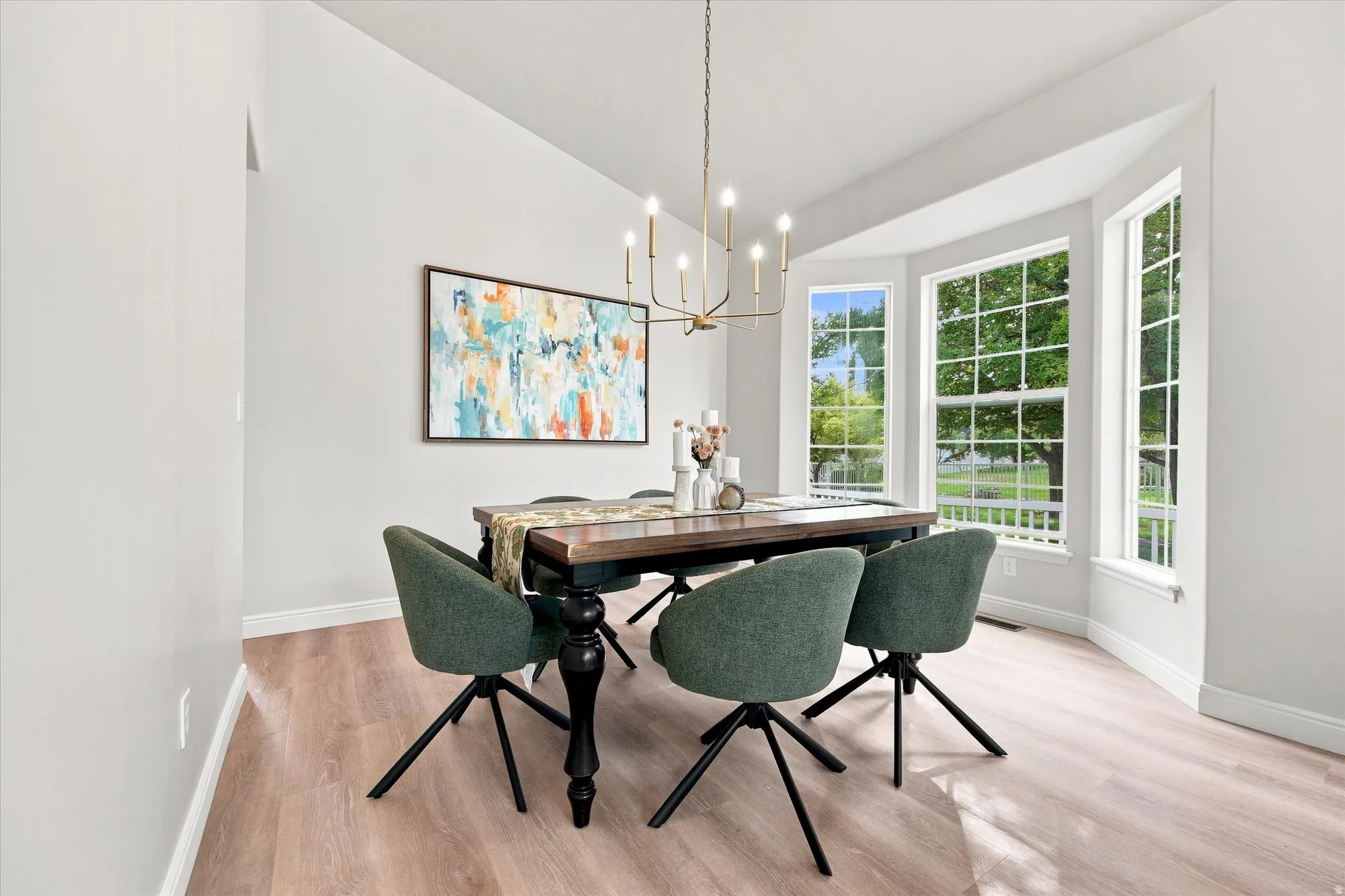 Vaulted ceiling, wood-finish flooring, bay window, chandelier lighting, and light-toned walls