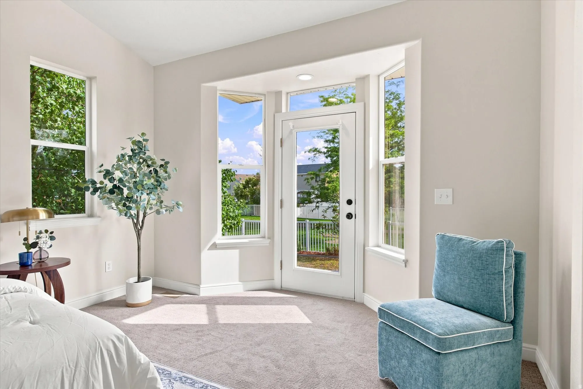Carpeted room with multiple windows, a bay window feature, and a glass-paneled exterior door