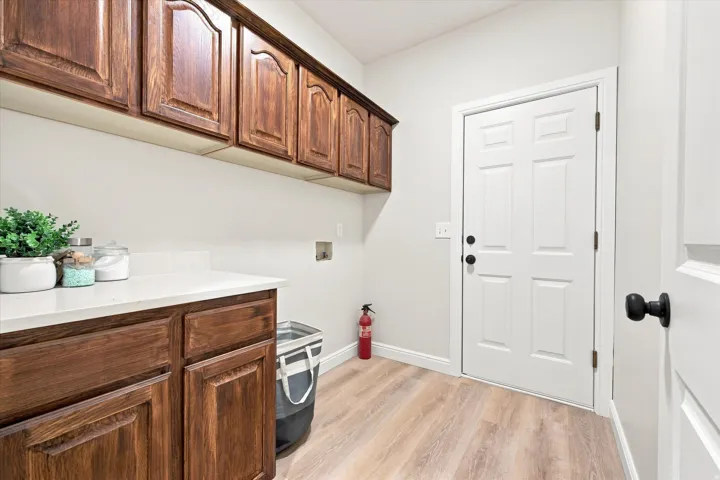 Wood-finish flooring, white walls, and a white door with matte black hardware