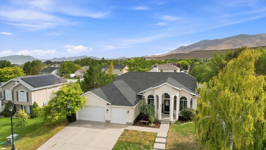 Exterior featuring a prominent arched entry, two-car garage, and mature landscaping