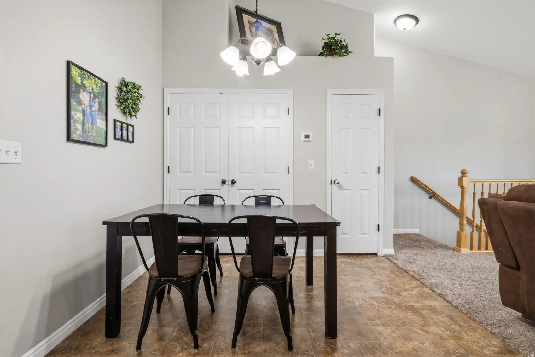 Vaulted ceiling with an overhead light fixture, wood-finish flooring, and white paneled doors