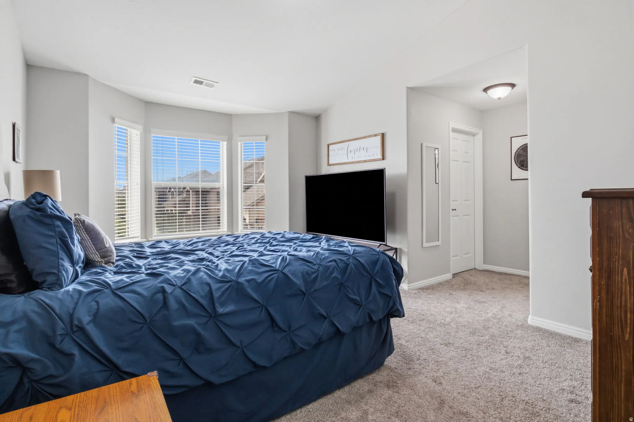 Bay window with multiple panels, neutral carpet flooring, recessed ceiling light, and a built-in closet with a white paneled door