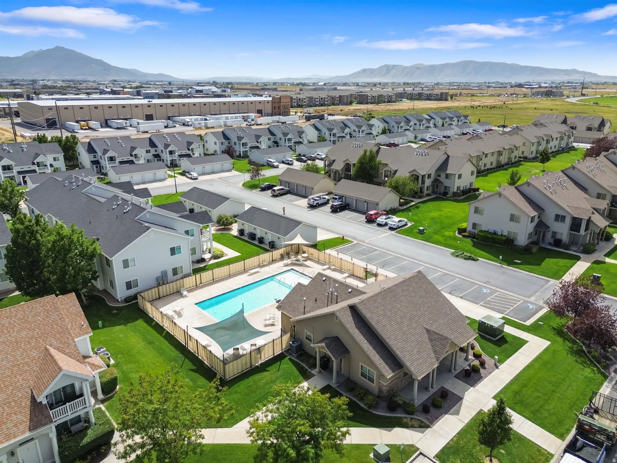 Community featuring a fenced outdoor swimming pool, adjacent clubhouse, and ample green space