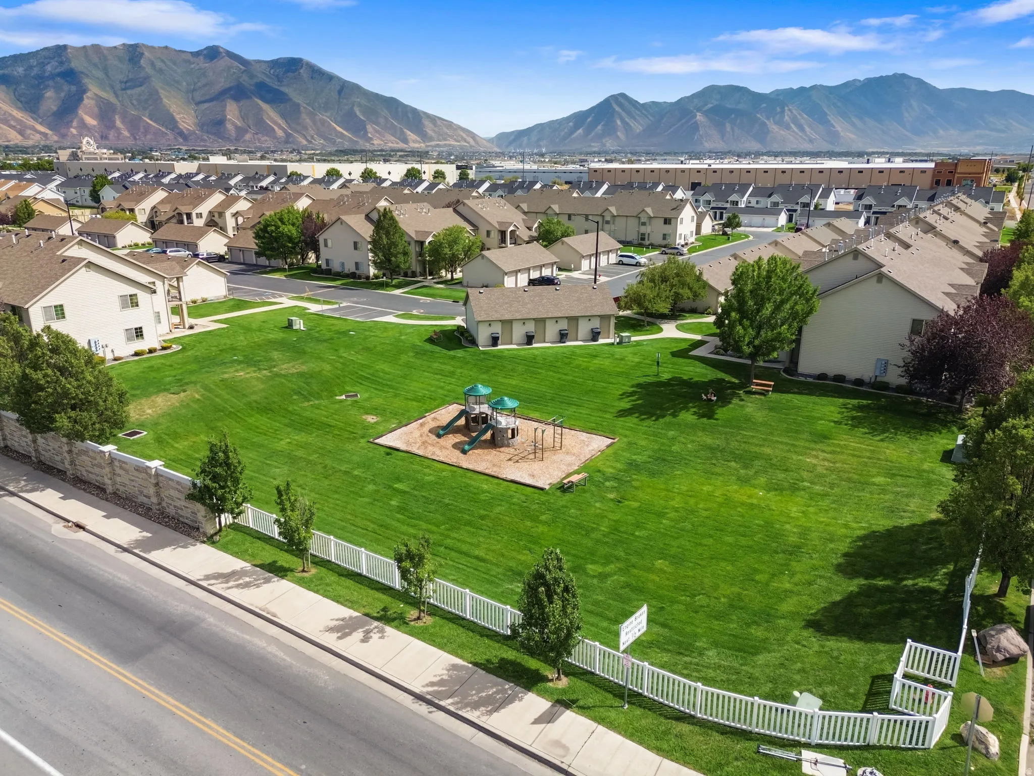 Expansive green space featuring a playground structure and surrounding residential properties