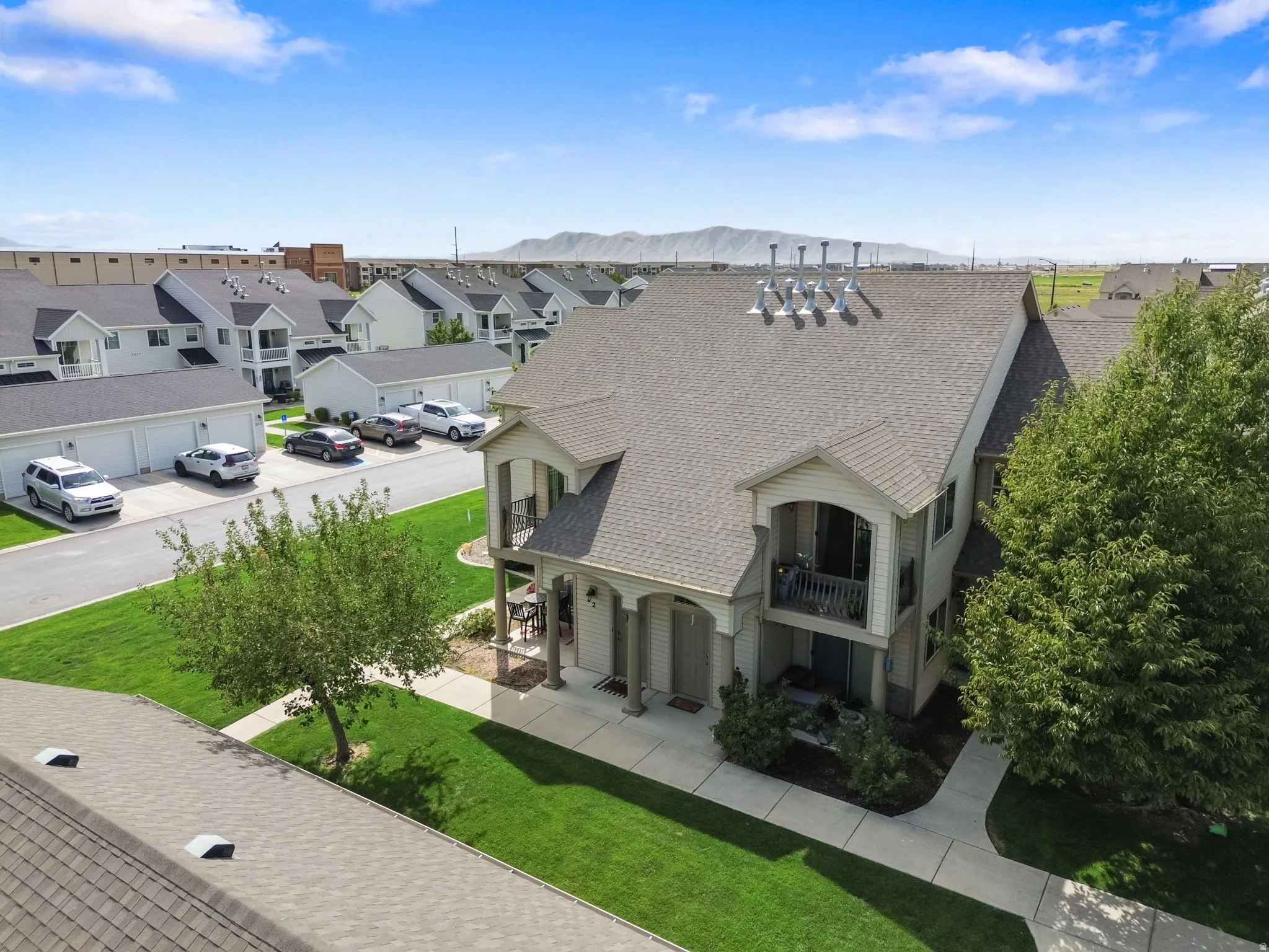 Two-story property featuring a covered porch, upper-level balcony, and mature trees