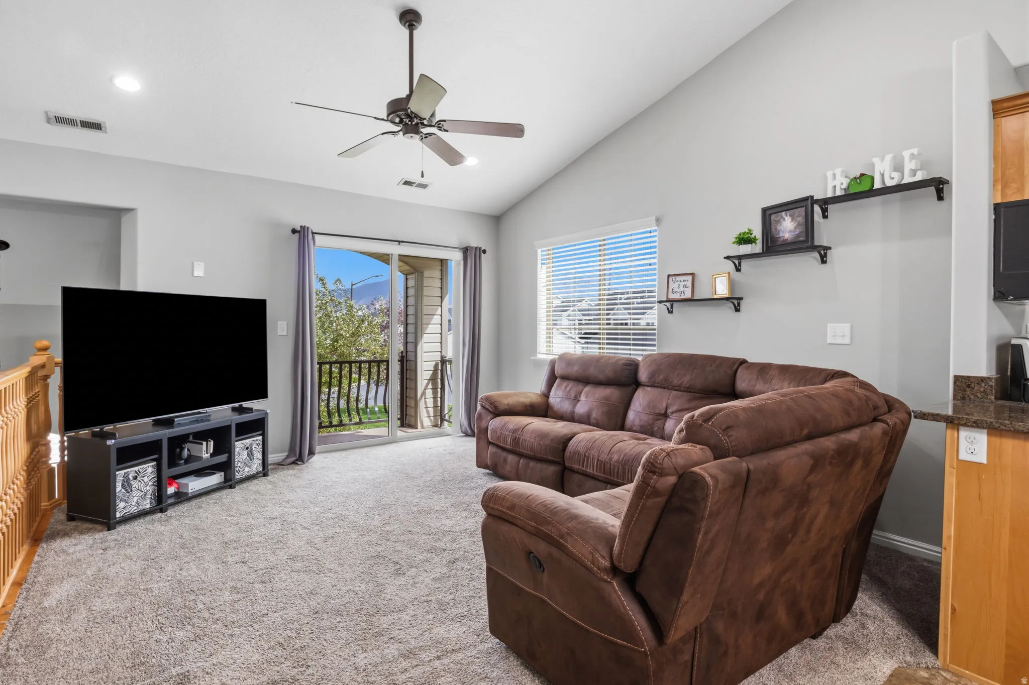 Vaulted ceiling, ceiling fan, recessed lighting, sliding glass door, and built-in shelving