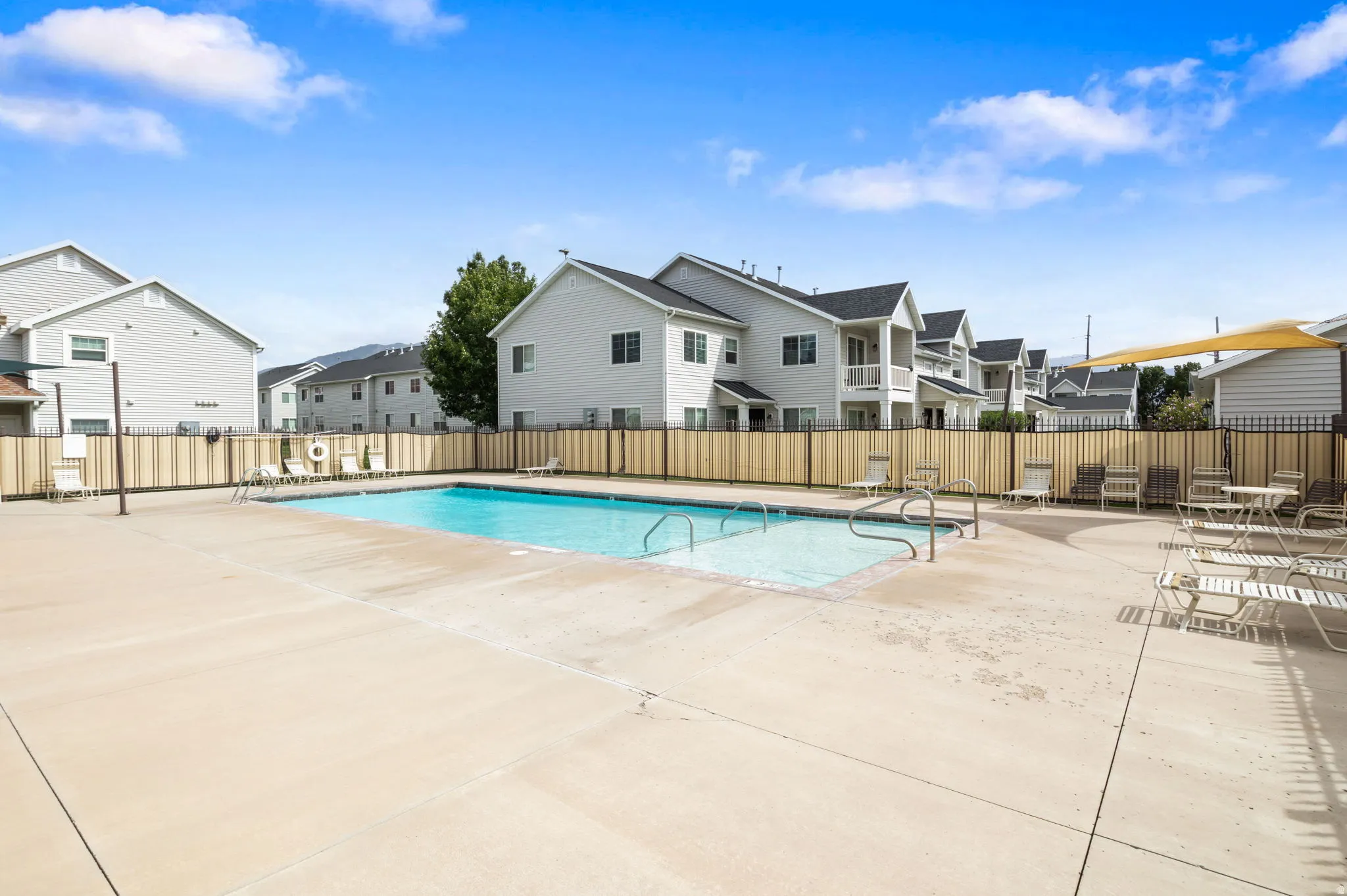 Outdoor swimming pool surrounded by a paved deck and privacy fencing