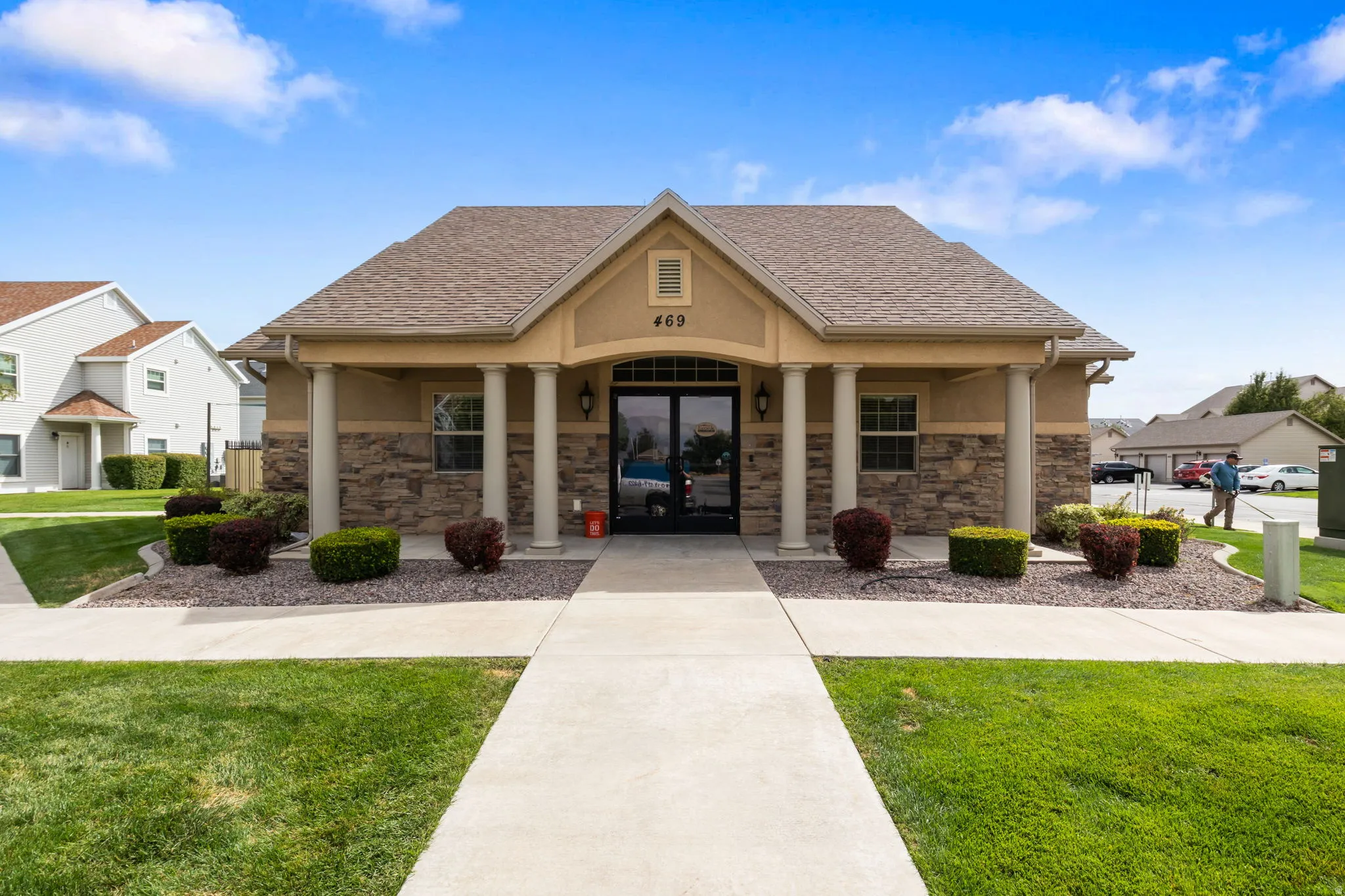 Building facade with stone accents, stucco finish, a covered entry, and decorative pillars