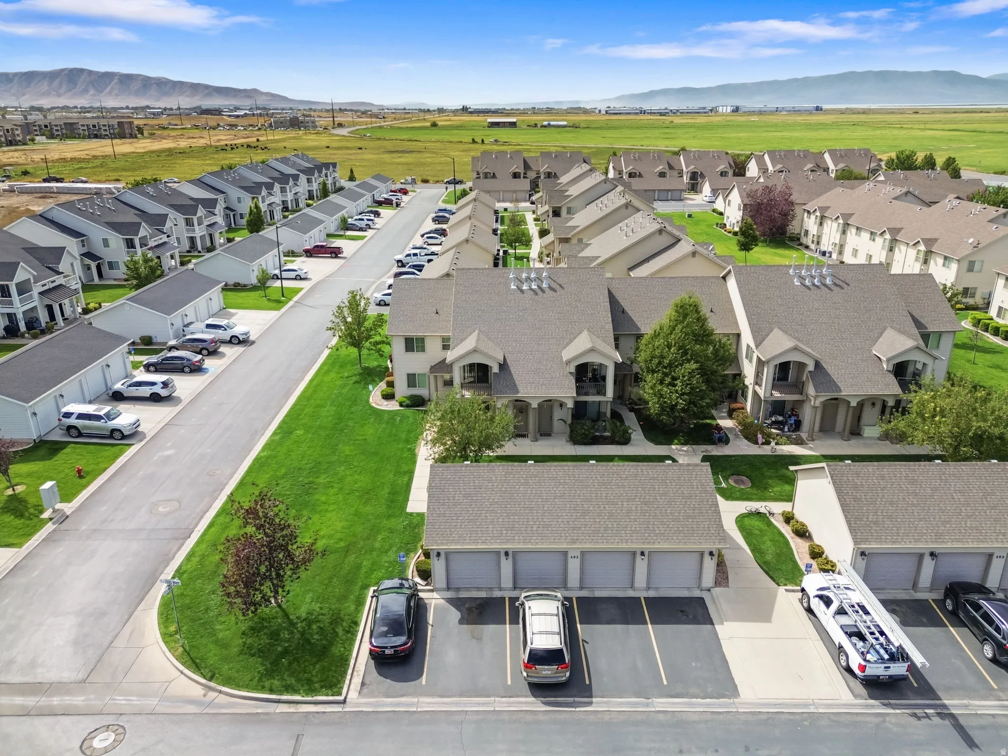 Residential community featuring pitched roofs, attached garages, paved roads, and landscaped green spaces